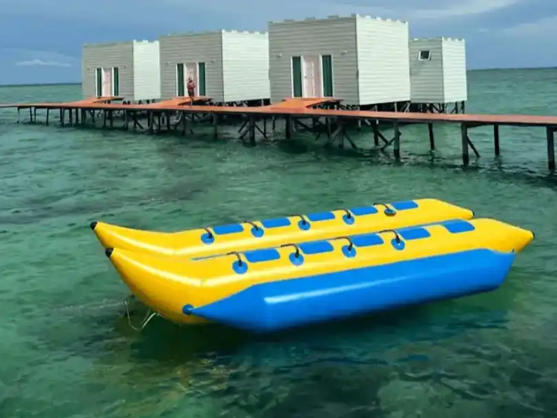 Yellow and blue banana boat floating on the clear water ready for guests outside the overwater chalets at Danglai Resort, Semporna