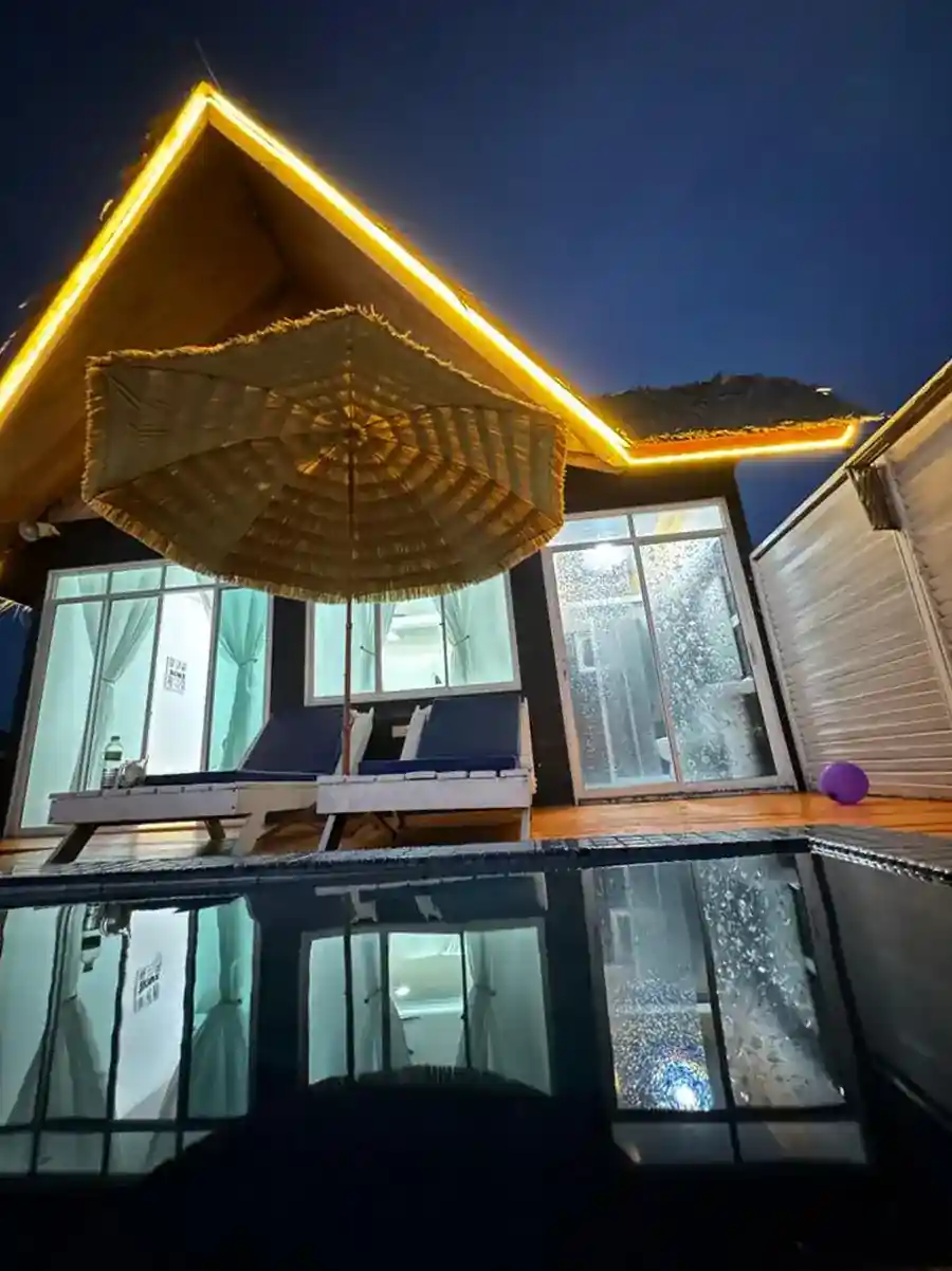 Beautiful night view of an illuminated water chalet at Danglai Resort, Semporna, showing the private balcony, plunge pool, and sun loungers.