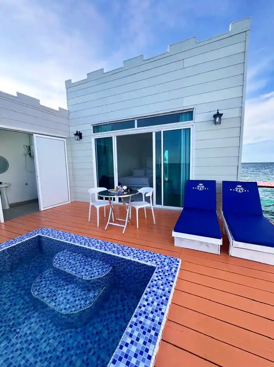 Exterior view of a premium water chalet at Danglai Resort, Semporna, featuring a private wooden balcony, tiled plunge pool, and blue sun loungers.