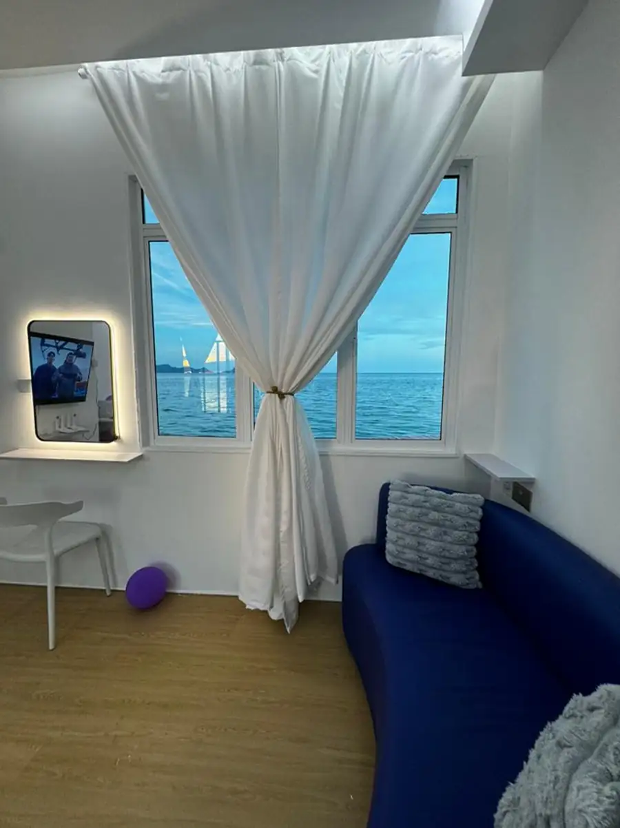 Relaxing lounge area inside an oceanfront water chalet at Danglai Resort Semporna with a modern blue sofa and direct views of the vibrant blue sea.