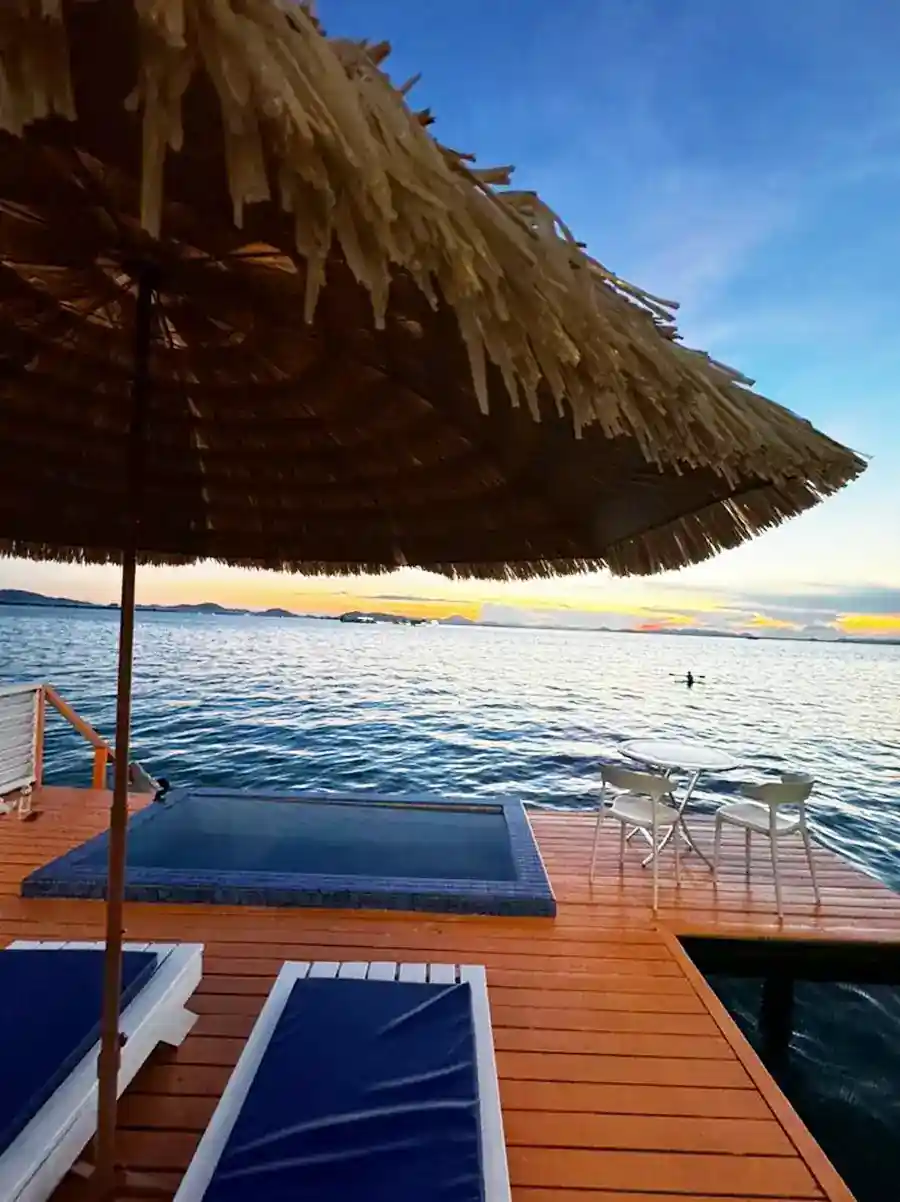 Stunning sunset view from a private overwater wooden balcony with a plunge pool, sun loungers, and thatched umbrella at Danglai Resort in Semporna.
