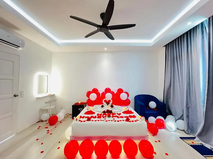Beautifully decorated honeymoon suite at Danglai Resort Semporna featuring red balloons, rose petals, and towel swans on a comfortable bed.